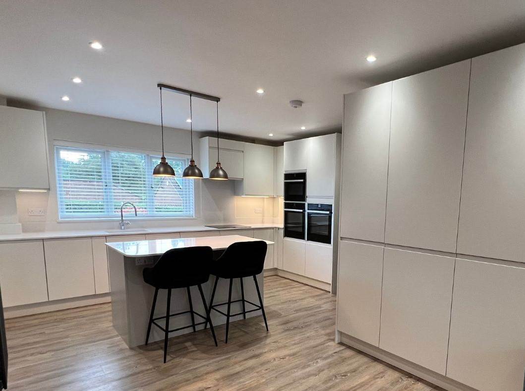 A modern kitchen in a Fleet home featuring sleek, true handle-less doors with a rail system